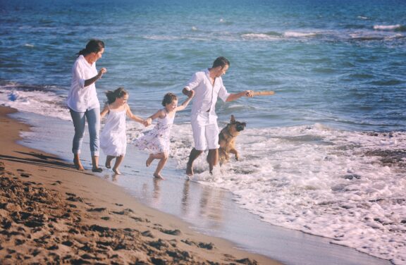 happy family playing with dog on beach